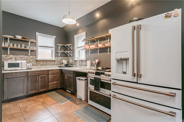 kitchen featuring pendant lighting, light tile patterned flooring, sink, white appliances, and backsplash