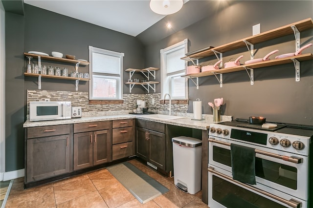 kitchen with light stone counters, sink, light tile patterned floors, tasteful backsplash, and double oven range