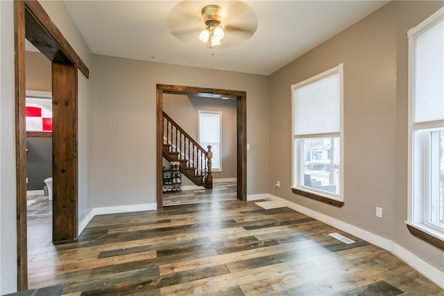 empty room with ceiling fan, dark hardwood / wood-style floors, and a healthy amount of sunlight