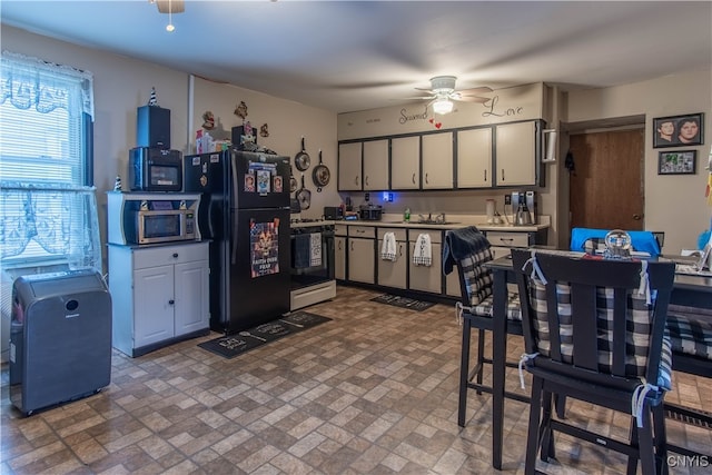 kitchen featuring sink, gas range gas stove, ceiling fan, and black fridge