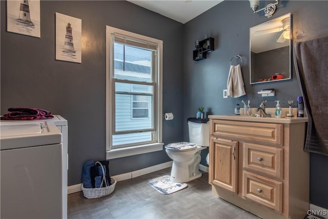 bathroom featuring baseboards, toilet, washer / clothes dryer, and vanity
