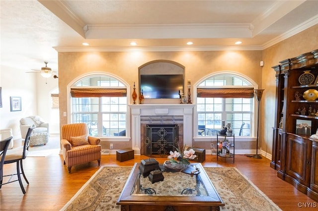 living room featuring ceiling fan, a fireplace, light hardwood / wood-style floors, and ornamental molding