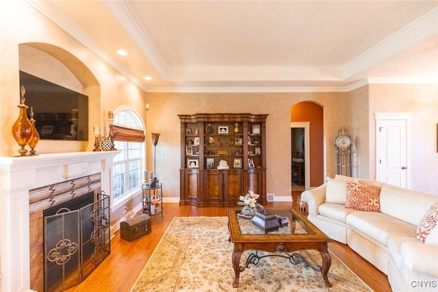 living room featuring light hardwood / wood-style flooring, ornamental molding, and a brick fireplace