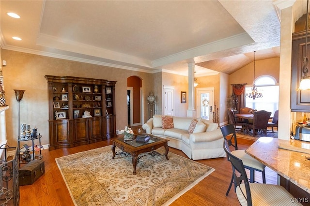 living room featuring wood-type flooring, ornamental molding, a tray ceiling, and a chandelier