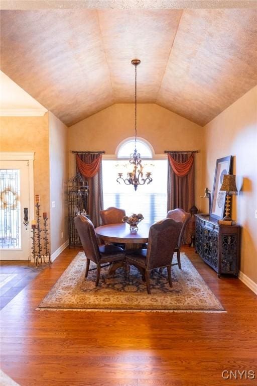 dining space featuring hardwood / wood-style flooring, a chandelier, and vaulted ceiling