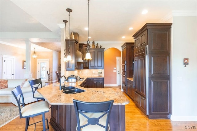 kitchen featuring kitchen peninsula, decorative light fixtures, ornate columns, and sink