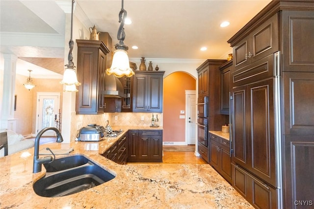 kitchen with light stone counters, ornamental molding, sink, pendant lighting, and light hardwood / wood-style floors