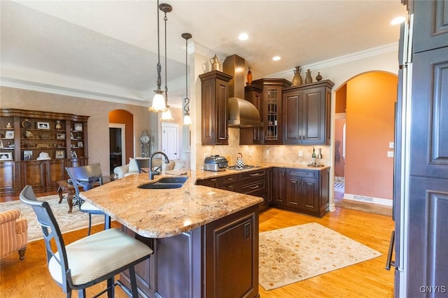 kitchen with dark brown cabinets, light hardwood / wood-style floors, crown molding, and sink