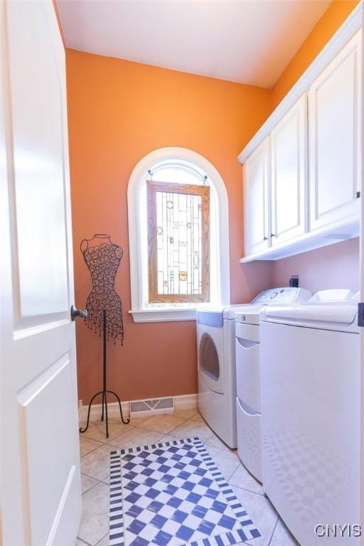 washroom with washer and dryer, light tile patterned floors, and cabinets