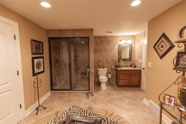 bathroom with tile patterned floors, vanity, tile walls, toilet, and a shower with shower door