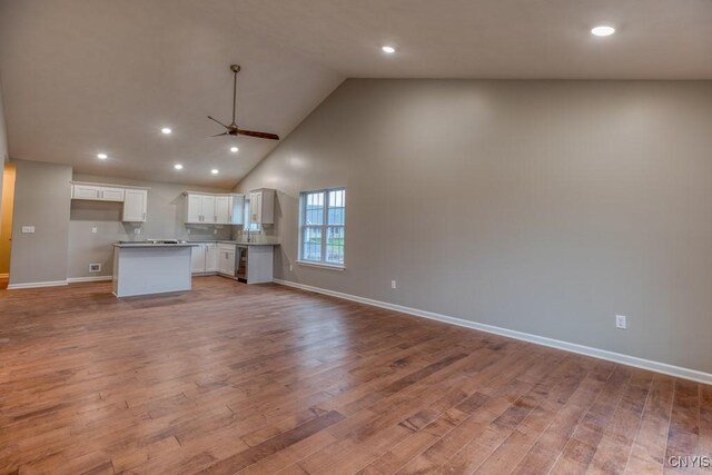 unfurnished living room featuring light hardwood / wood-style floors, ceiling fan, and high vaulted ceiling