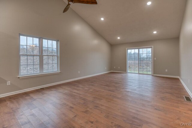 empty room with high vaulted ceiling, ceiling fan, and light hardwood / wood-style flooring