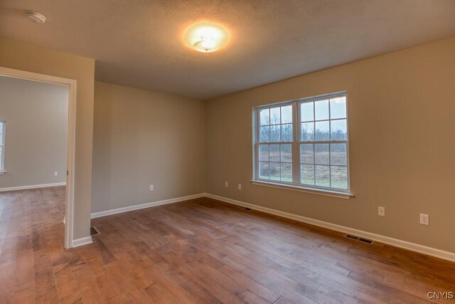 unfurnished room featuring a textured ceiling and light wood-type flooring