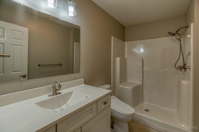 bathroom featuring vanity, a shower, and toilet