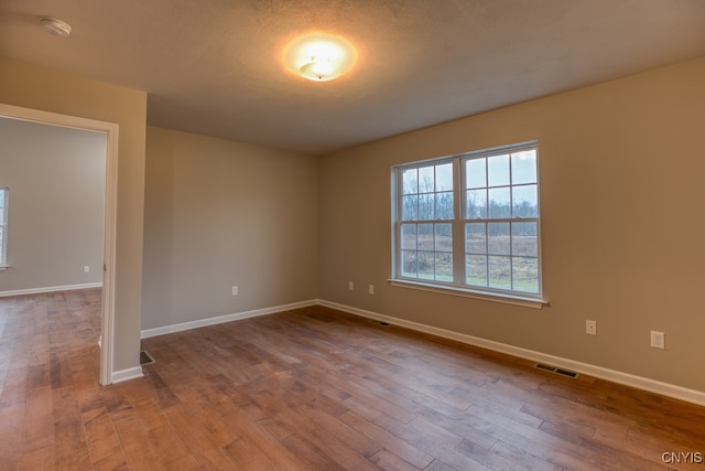 spare room featuring a textured ceiling and light hardwood / wood-style flooring