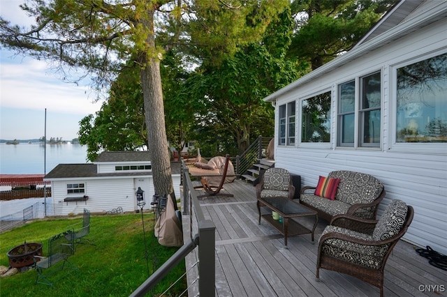 wooden terrace featuring a lawn, a water view, and an outdoor living space with a fire pit