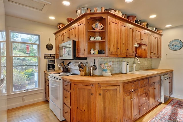 kitchen featuring appliances with stainless steel finishes, light hardwood / wood-style floors, backsplash, butcher block countertops, and sink