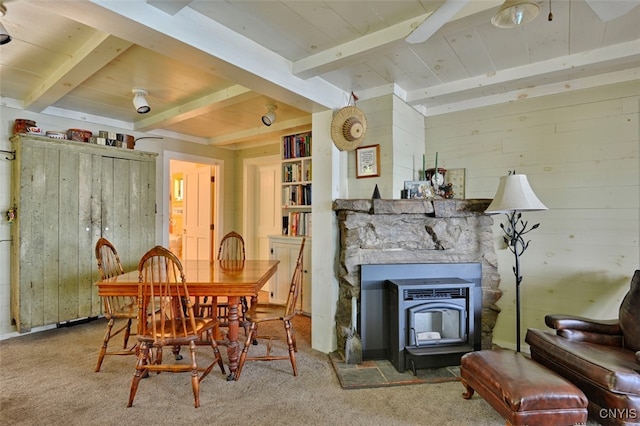 carpeted dining area with a wood stove, beam ceiling, and a fireplace