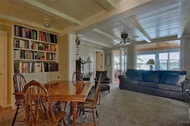 dining area featuring carpet, beamed ceiling, and ceiling fan