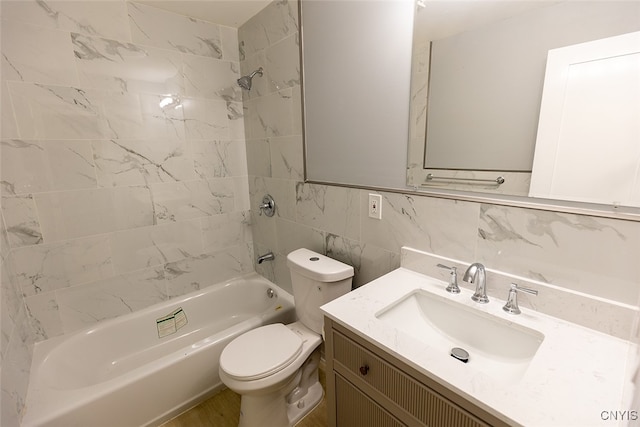 full bathroom featuring tiled shower / bath, vanity, tile walls, and toilet