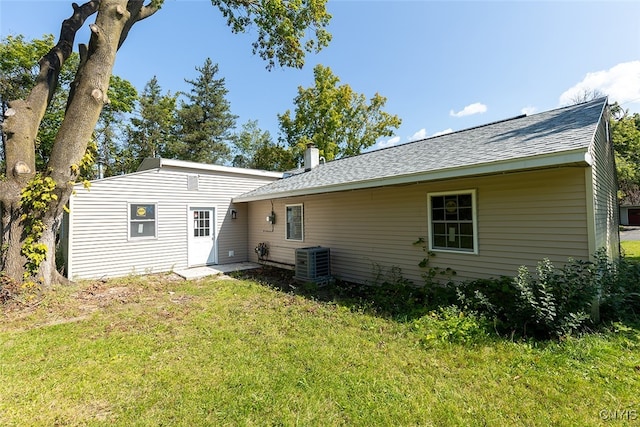 rear view of property with a lawn and cooling unit