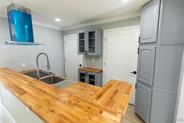 kitchen featuring light hardwood / wood-style floors, gray cabinets, ventilation hood, wood counters, and sink