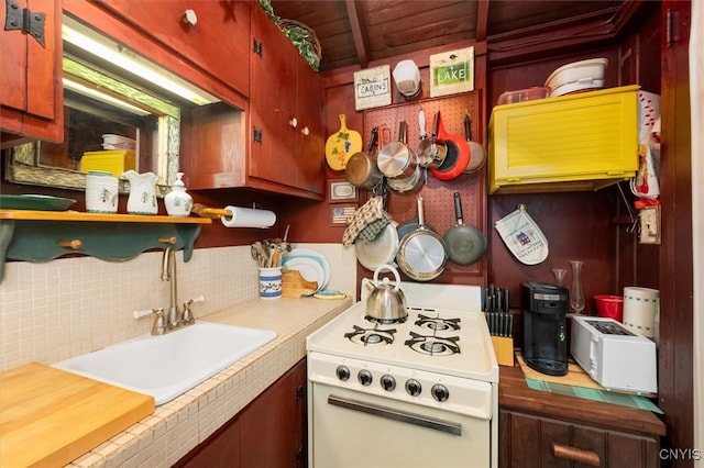 kitchen with wood ceiling, tile counters, sink, decorative backsplash, and white range oven