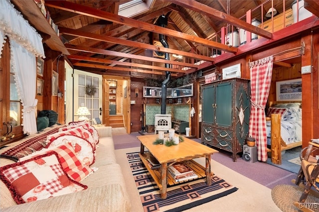 carpeted living room with vaulted ceiling with beams, wood walls, and a wood stove