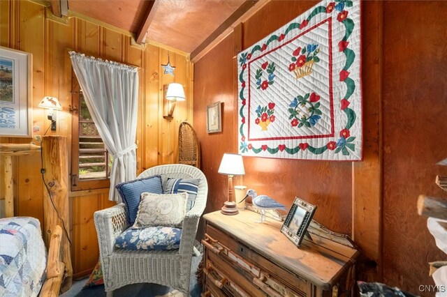 sitting room featuring lofted ceiling and wood walls