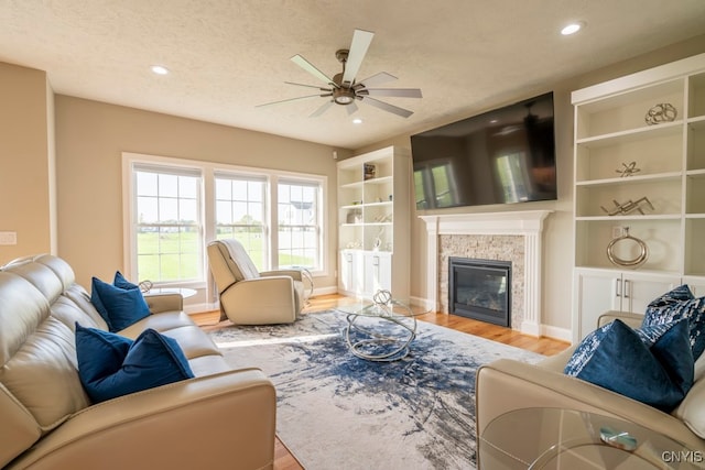 living room featuring ceiling fan, a textured ceiling, and light wood-type flooring