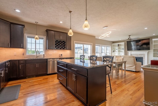 kitchen with a textured ceiling, a breakfast bar area, a kitchen island, and stainless steel dishwasher