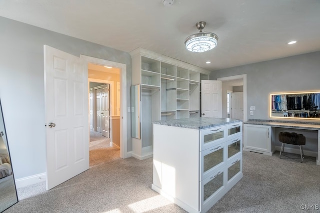 kitchen with white cabinets, light colored carpet, and stone counters