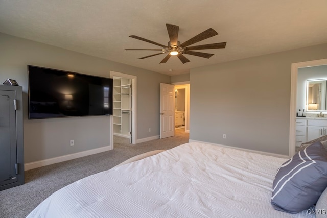 carpeted bedroom with ensuite bathroom, ceiling fan, a walk in closet, and a closet