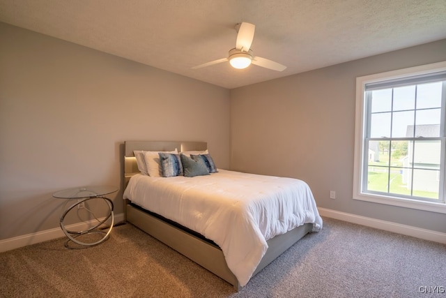 carpeted bedroom with ceiling fan and a textured ceiling