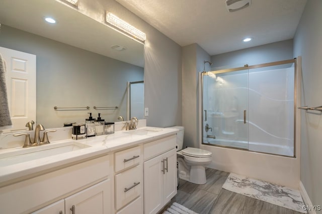 full bathroom with bath / shower combo with glass door, toilet, and vanity