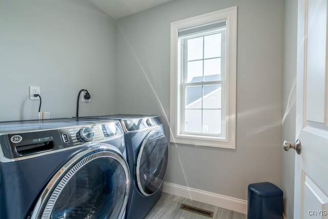 laundry area with separate washer and dryer and light wood-type flooring