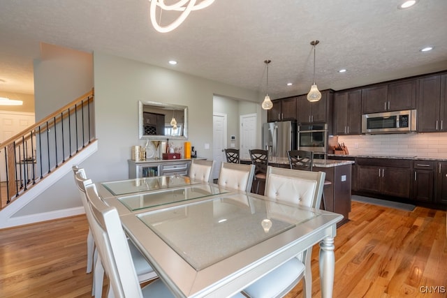 kitchen featuring stainless steel appliances, light hardwood / wood-style floors, a center island, and hanging light fixtures