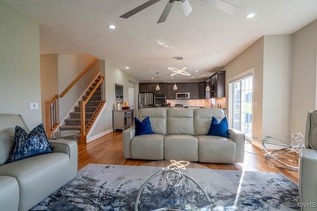 living room with light wood-type flooring, a textured ceiling, and ceiling fan