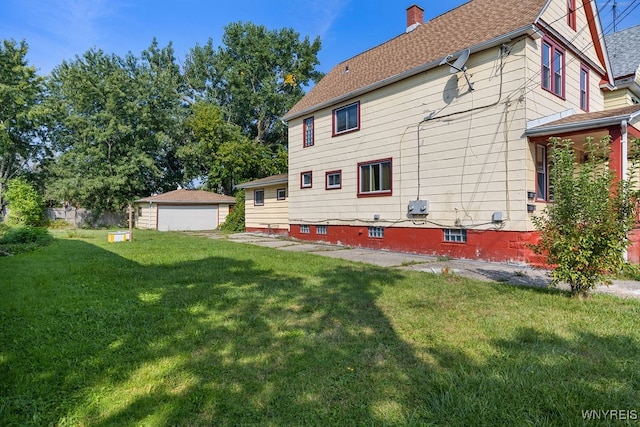 rear view of house featuring a garage, an outdoor structure, and a lawn