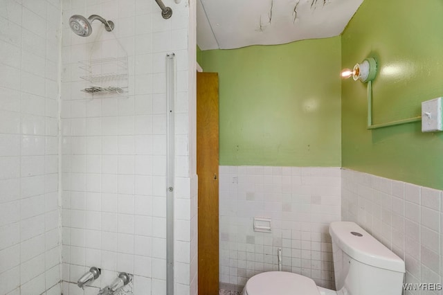 bathroom featuring tiled shower, toilet, and tile walls