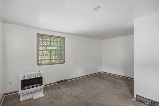 empty room featuring dark colored carpet and heating unit