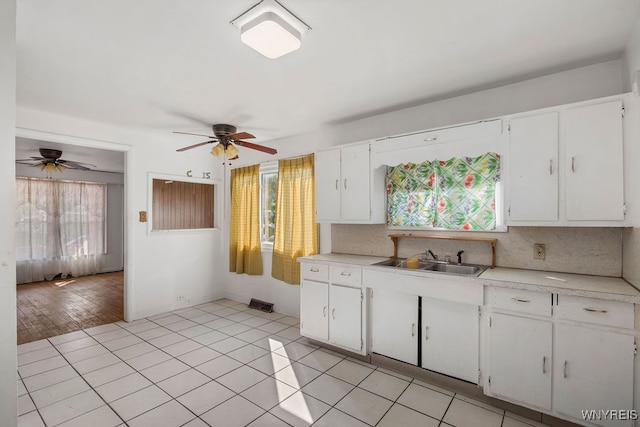 kitchen with tasteful backsplash, sink, white cabinets, and light hardwood / wood-style flooring