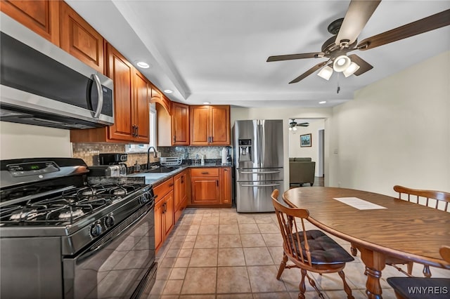 kitchen featuring light tile patterned flooring, sink, decorative backsplash, appliances with stainless steel finishes, and ceiling fan