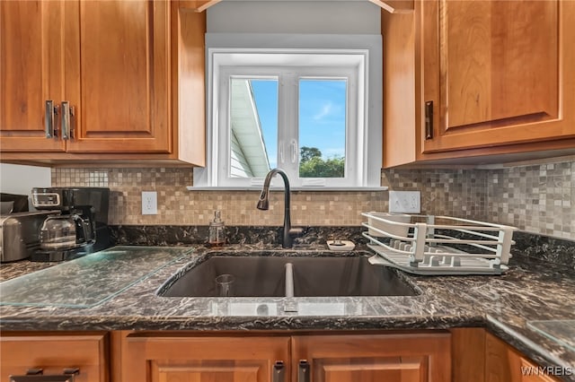 kitchen featuring dark stone countertops, backsplash, and sink