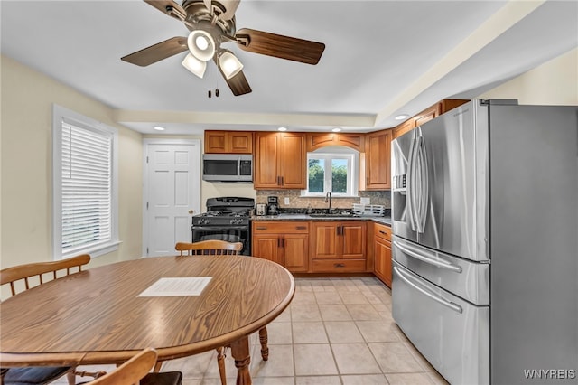 kitchen featuring tasteful backsplash, light tile patterned floors, stainless steel appliances, ceiling fan, and sink