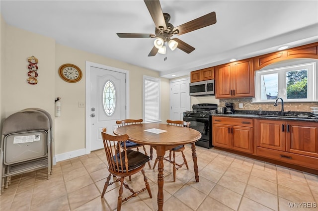 kitchen with ceiling fan, black gas stove, sink, light tile patterned floors, and decorative backsplash