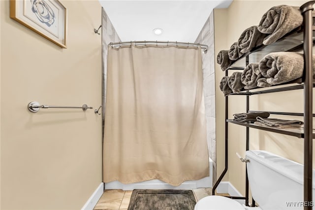 bathroom with shower / bath combo with shower curtain, toilet, and tile patterned flooring