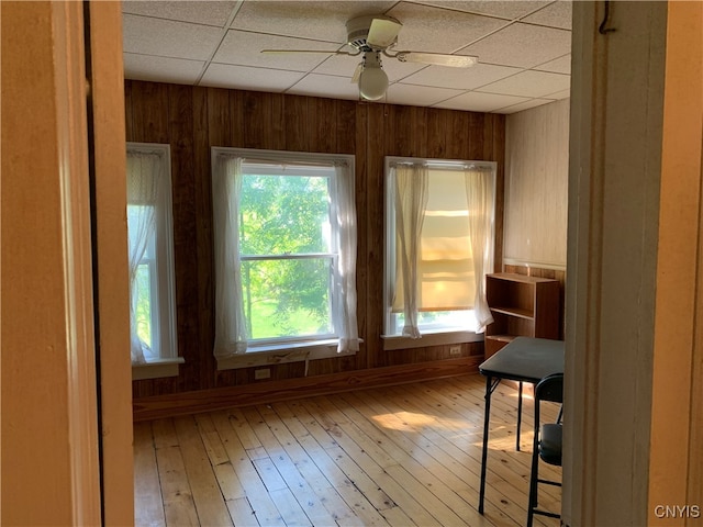 spare room featuring hardwood / wood-style flooring, wooden walls, ceiling fan, and plenty of natural light