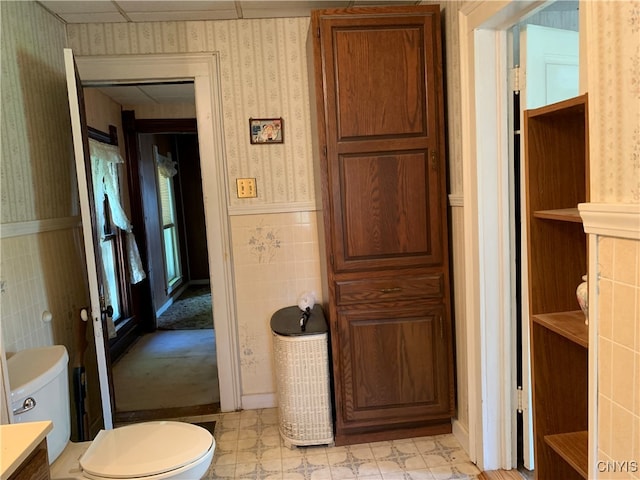 bathroom featuring vanity, tile walls, and toilet