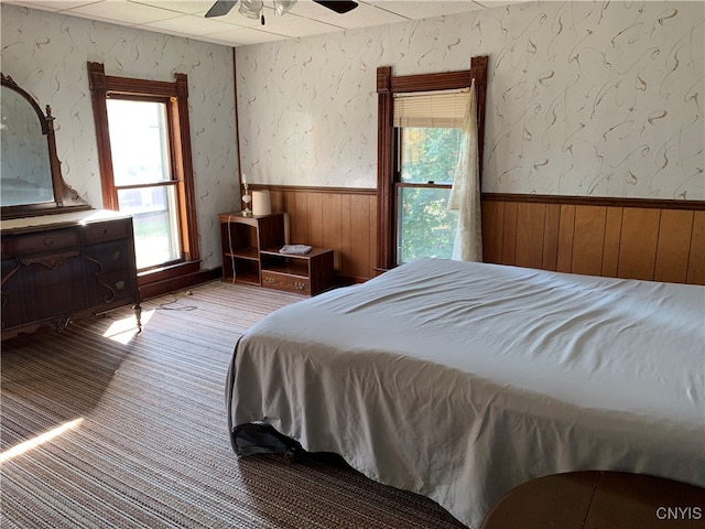 bedroom featuring ceiling fan and wood walls